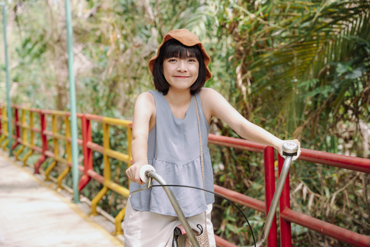 年轻的泰国亚裔女子骑自行车在乡间小路上旅行。本地旅行。