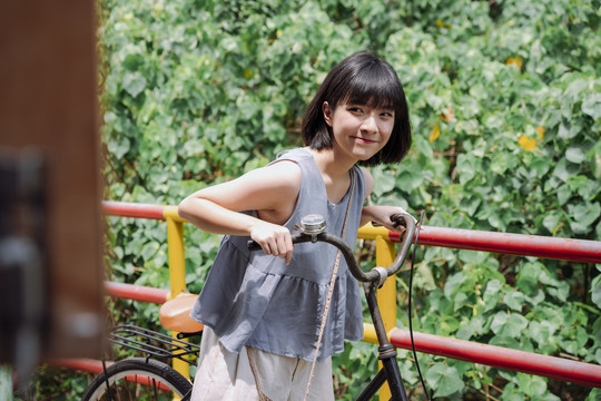 年轻的泰国亚裔女子在乡村小街骑自行车。本地旅行。