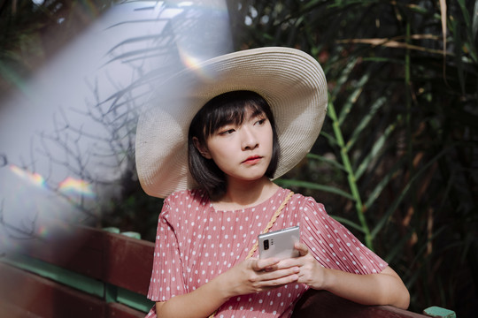 美丽的亚泰女人黑色短发戴着大帽子用智能手机。