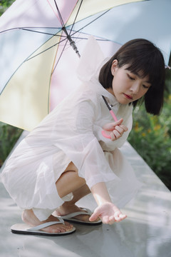 美丽的亚泰女子黑色短发，穿着雨衣，手持雨伞。坐姿。