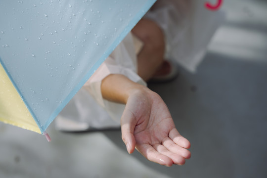 穿雨衣的女人的手紧握着，赤手空拳地触摸着雨水。