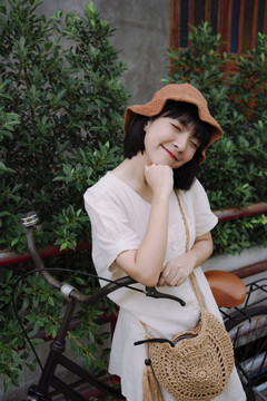 时尚写真-美丽的亚泰女人深色短发戴帽子在自行车上摆姿势。
