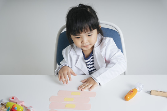 漂亮的泰国亚裔小孩扮演医生的角色检查医用绷带膏。