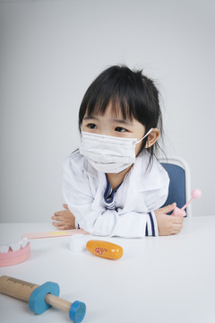 漂亮的泰国亚裔小孩戴着面具扮演医生和牙医的角色。