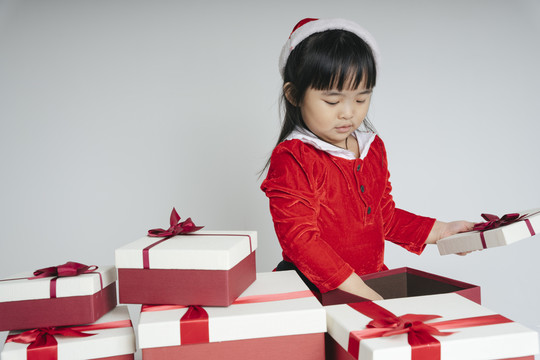 穿着圣诞老人制服的泰国亚裔漂亮小姑娘拿着圣诞礼盒庆祝雪景节。