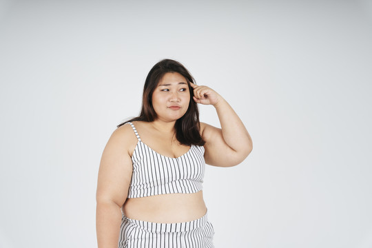 体贴的亚洲胖乎乎的女人指着某个东西思考的画像。