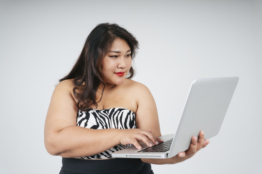 亚洲胖乎乎的女商人在白色背景下使用笔记本电脑的肖像。