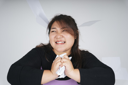 愤怒的亚洲胖乎乎的女商人用双手撕碎了纸。