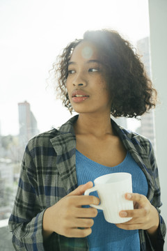 欢快的非洲卷发女子手持咖啡杯的肖像。
