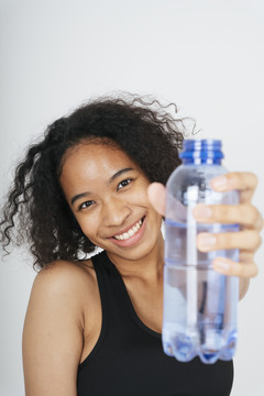 在白色背景上拿着塑料水瓶的非洲人的特写肖像。