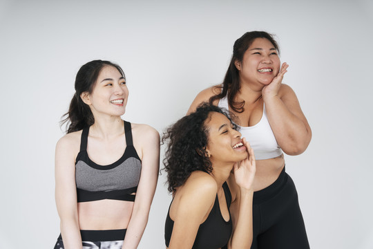 三位不同肤色的亚裔和非裔女性身着白色背景的运动胸罩。