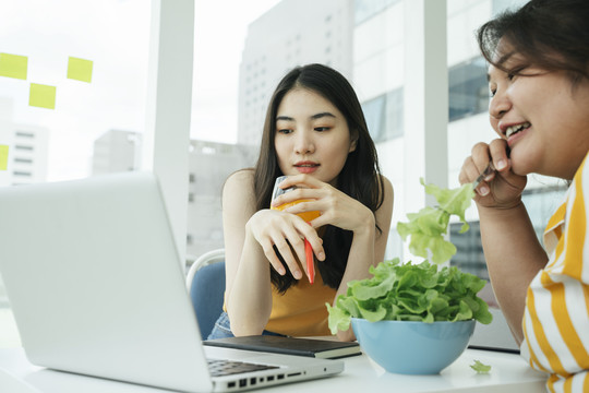 亚洲商界女性午餐吃健康食品，看笔记本电脑。