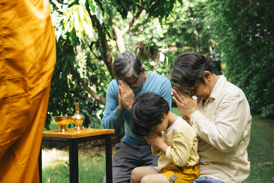 亚洲家庭在施舍后向僧侣致意。