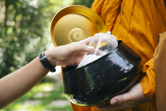 在公园里，人们用僧侣的碗来分发施舍。