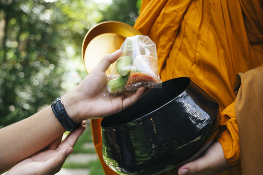 在公园里，人们用僧侣的碗来分发施舍。