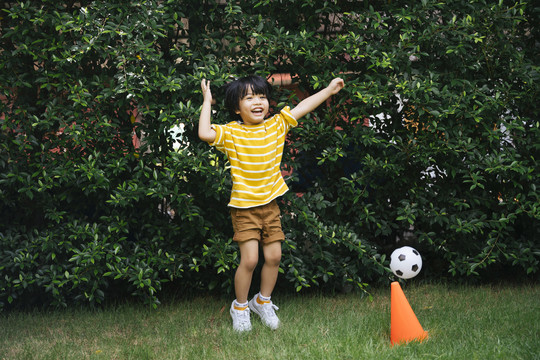 亚洲小孩在公园的足球场进球后感到很高兴。