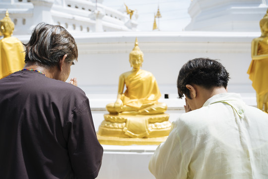 后视图-亚洲老年夫妇在泰国寺庙拜佛。