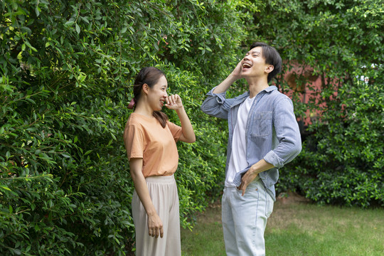 快乐的亚洲年轻夫妇在院子里互相交谈。