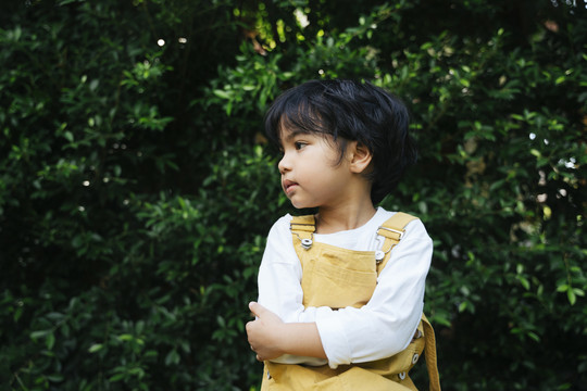 帅气的黑发亚裔小孩坐在院子里的椅子上。