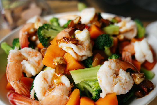 把海鲜和虾、蔬菜一起放在木盘上翻炒。