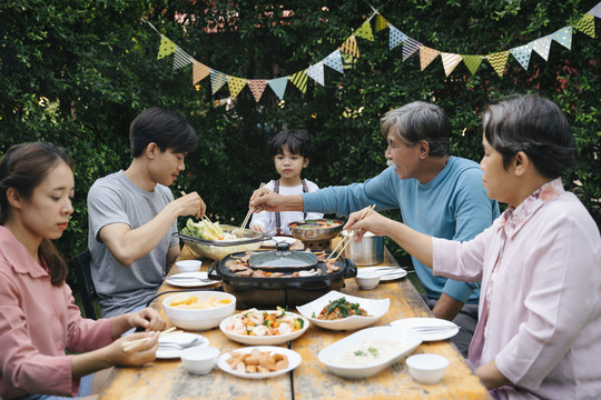 快乐的亚洲家庭喜欢在院子里一起吃泰国烧烤和当地食物。