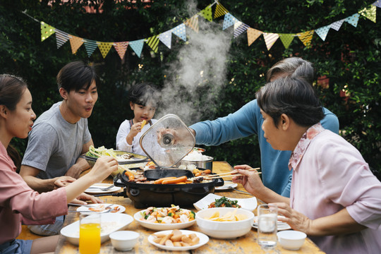 亚洲家庭喜欢在院子里一起吃泰国烤肉。