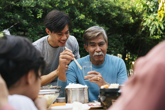 快乐的父子俩在院子里享受着户外用餐的乐趣。