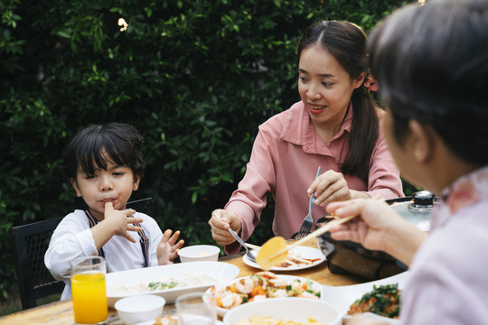 亚洲小孩和妈妈在院子里吃户外餐。