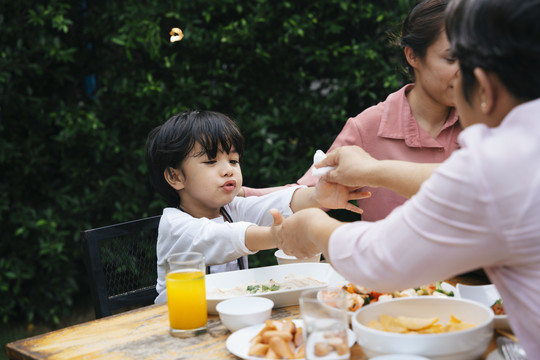 亚洲小孩和妈妈在院子里吃户外餐。