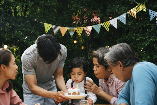 亚洲家庭在户外用蛋糕为孩子庆祝生日聚会。