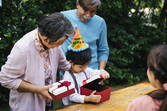 快乐的亚洲家庭在户外院子里一起庆祝孩子的生日聚会。