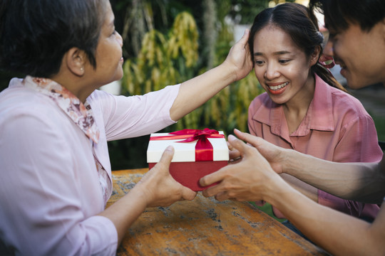 亚洲夫妇在特殊的日子给母亲送礼盒。