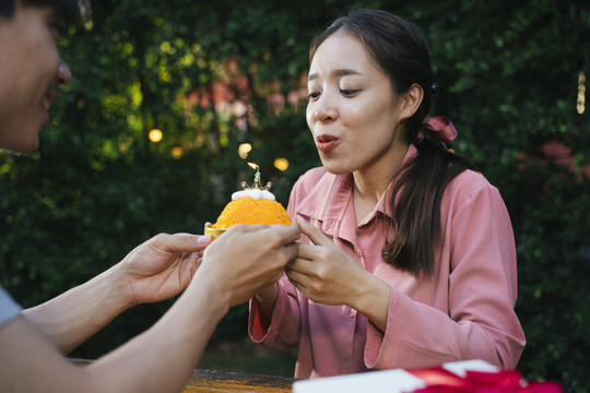 亚洲女人和男友用金线甜点蛋糕庆祝生日派对。