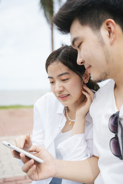 在户外使用智能手机地图应用程序的亚洲旅行情侣。