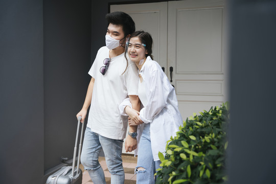一对可爱的亚洲夫妇在门口戴着口罩和面罩。