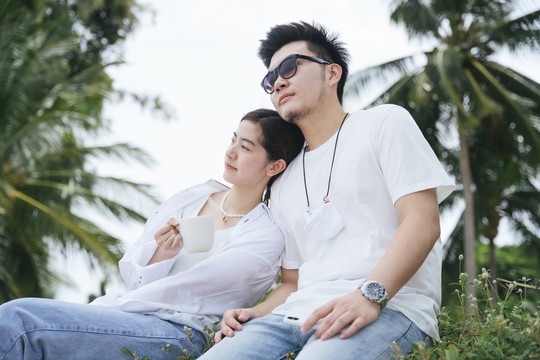 浪漫的亚洲情侣一起坐在沙滩上。