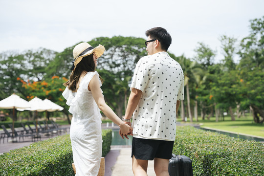 后视图-亚洲情侣旅行者牵手在公园里一起散步。