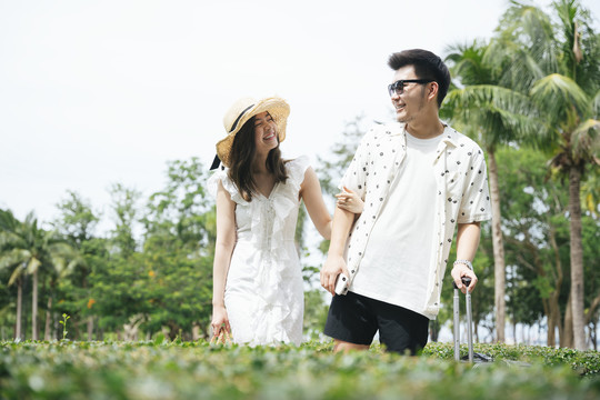 亚洲情侣旅行者手牵手在公园户外散步。