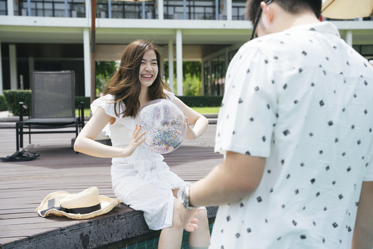 亚洲情侣旅行者喜欢一起在酒店游泳池玩塑料球。