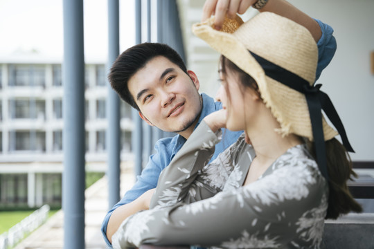 亚洲情侣旅行者站在酒店阳台上看风景。