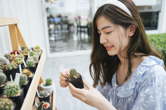 美丽的亚洲女农场主手持仙人掌壶。