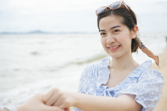 夏天，美丽的亚洲旅行家女人手牵着手在海滩上。