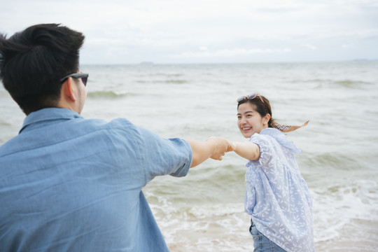 一对亚洲情侣在沙滩上牵着手。幸福时刻。
