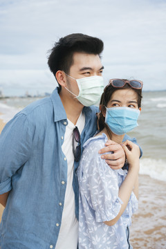 一对亚洲情侣在沙滩上拥抱的照片。