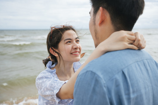 浪漫的亚洲情侣在沙滩上互相对视。