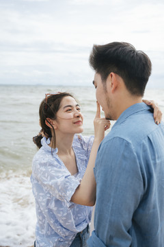 浪漫的亚洲情侣在沙滩上互相对视。