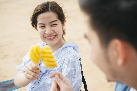 美丽的亚洲年轻旅女喜欢和男朋友在沙滩上吃菠萝。