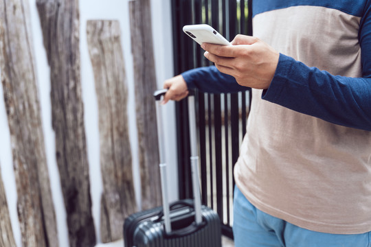 带着行李箱的旅行者用智能手机。用智能手机预订酒店和航班。