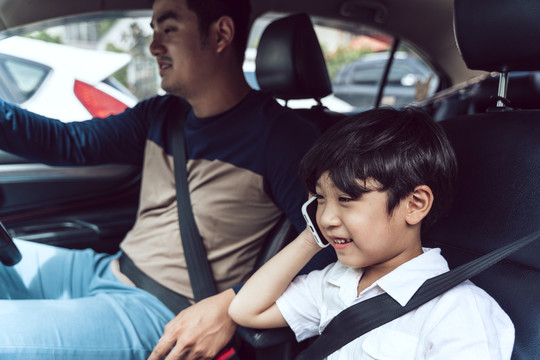 父亲开车时，亚裔儿子在车里打电话。