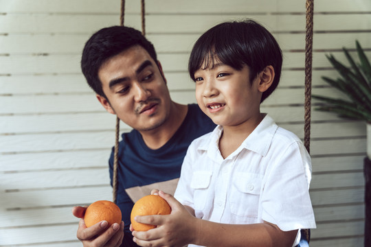 亚裔父子早餐或午餐都喜欢吃橘子。